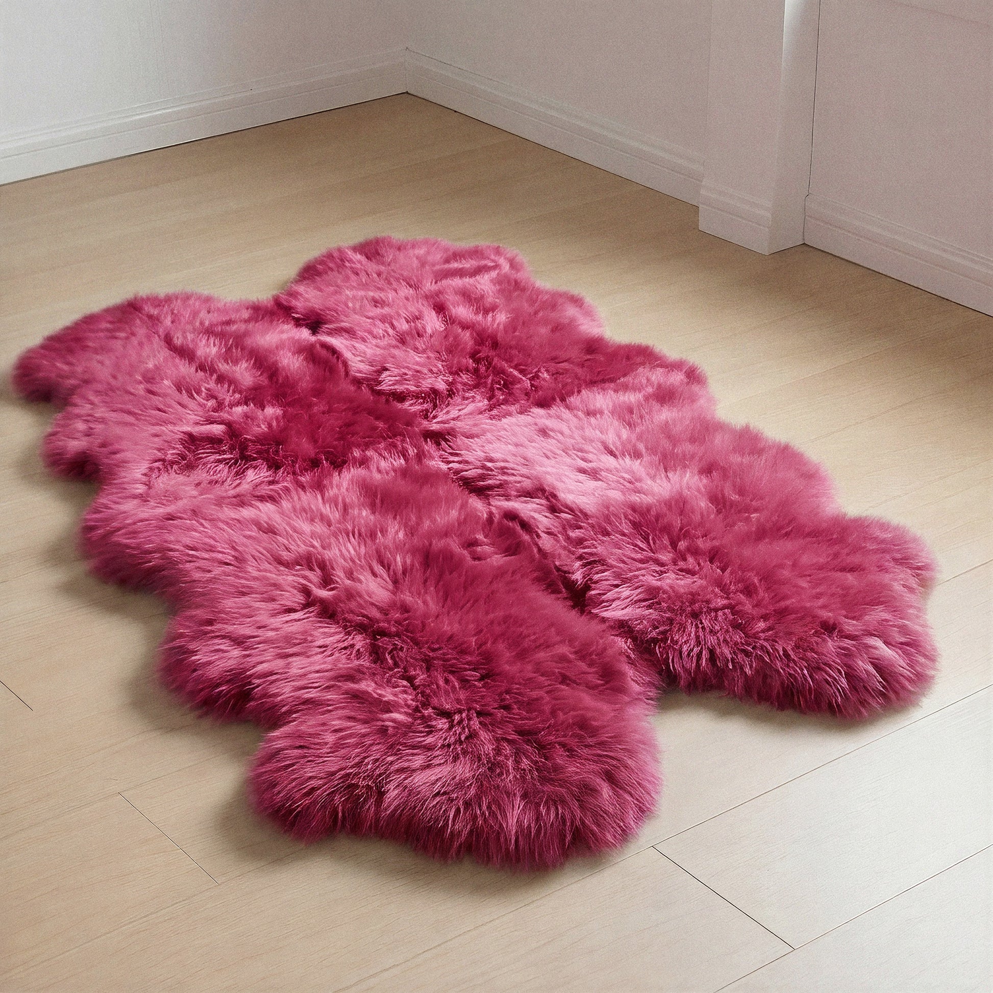 Fuchsia New Zealand sheepskin quad rug on wood floor