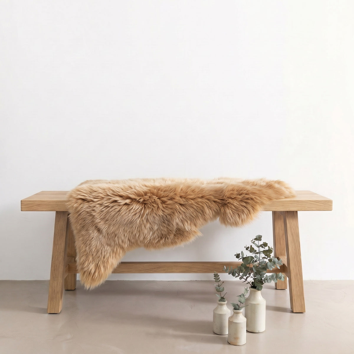 Honey sheepskin rug draped over an oak bench