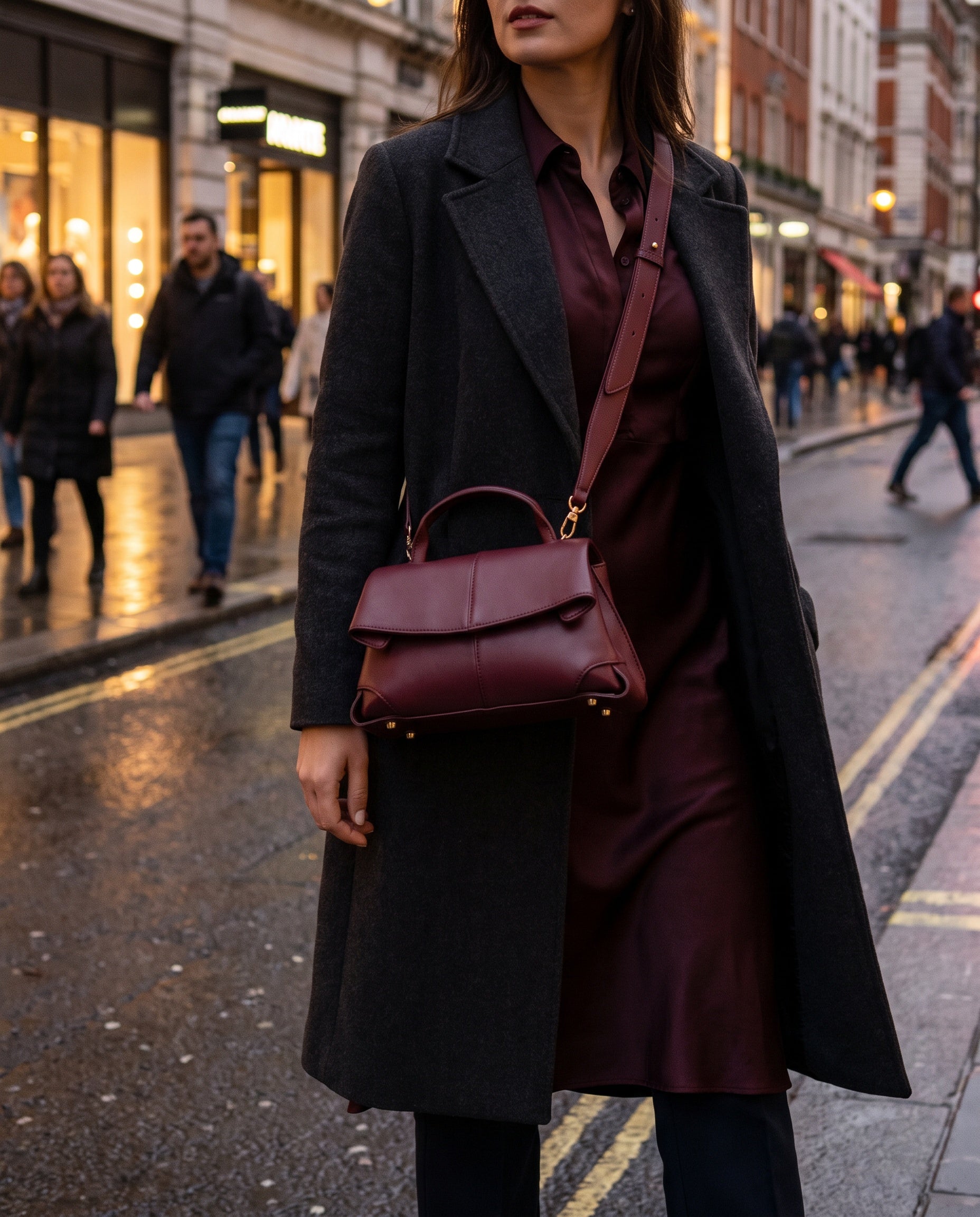 Woman with the Burgundy Fiorella bag crossbody on an evening city street