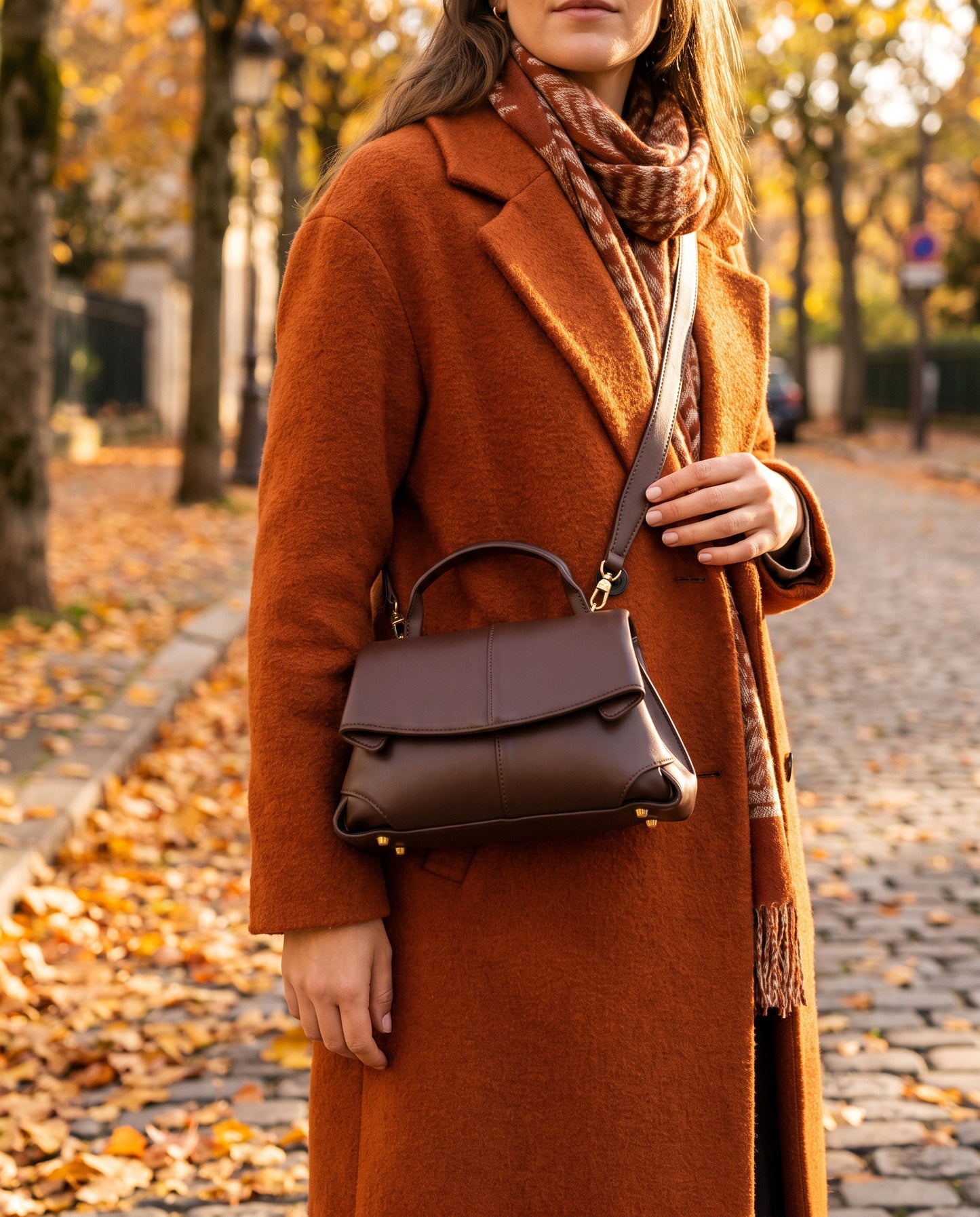 Woman with the Chocolate Fiorella bag crossbody on an autumn leaf-strewn street