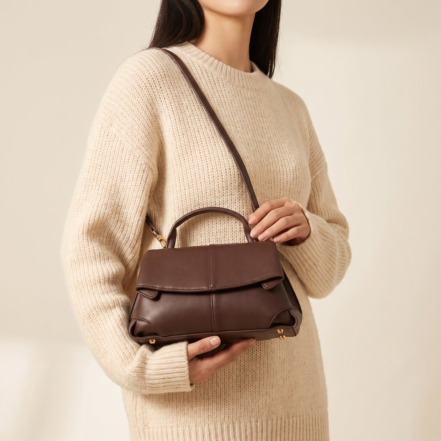 Model holding the Chocolate Fiorella mini leather baguette in both hands, studio shot