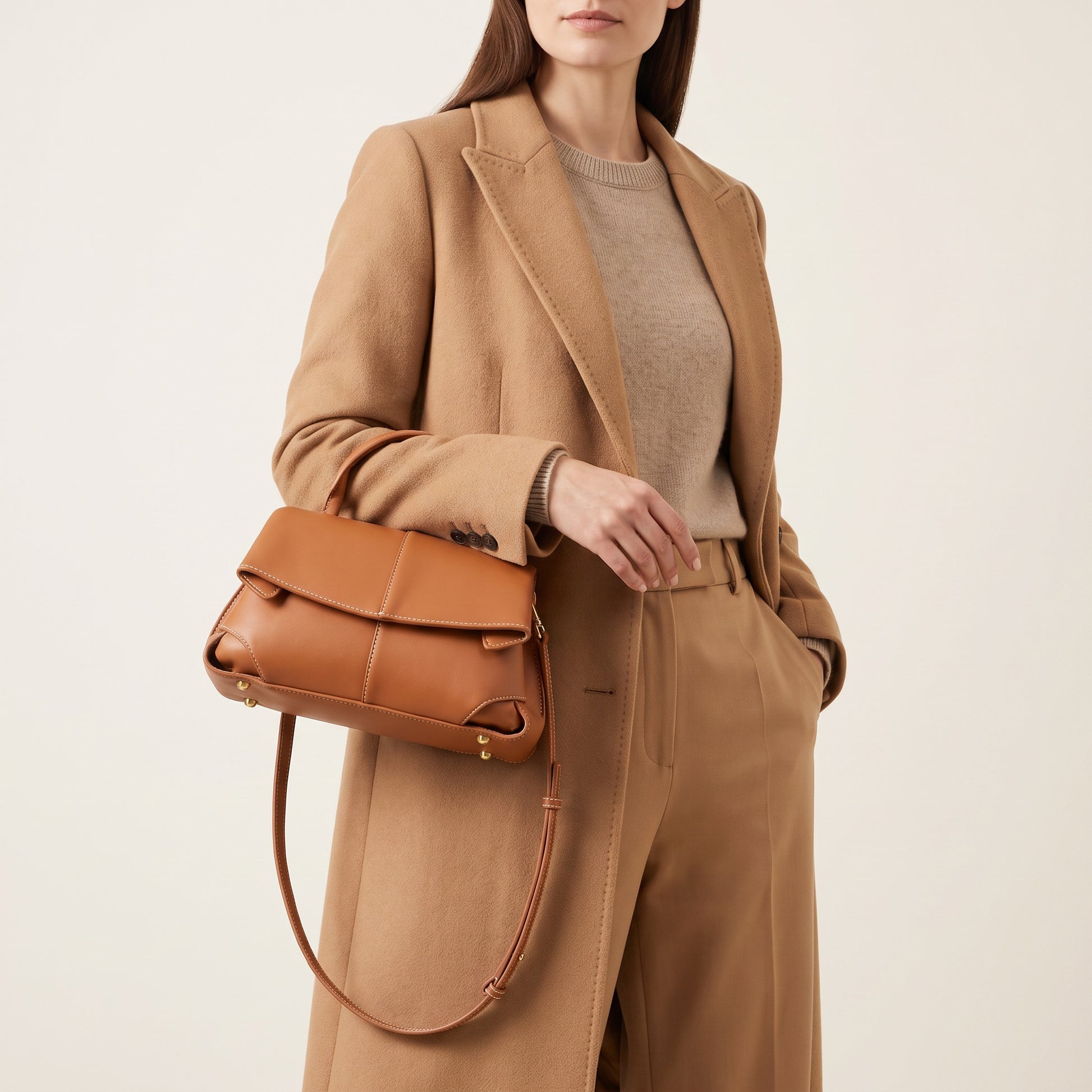 Model with the Cognac Fiorella mini leather baguette on the crook of her elbow, studio shot