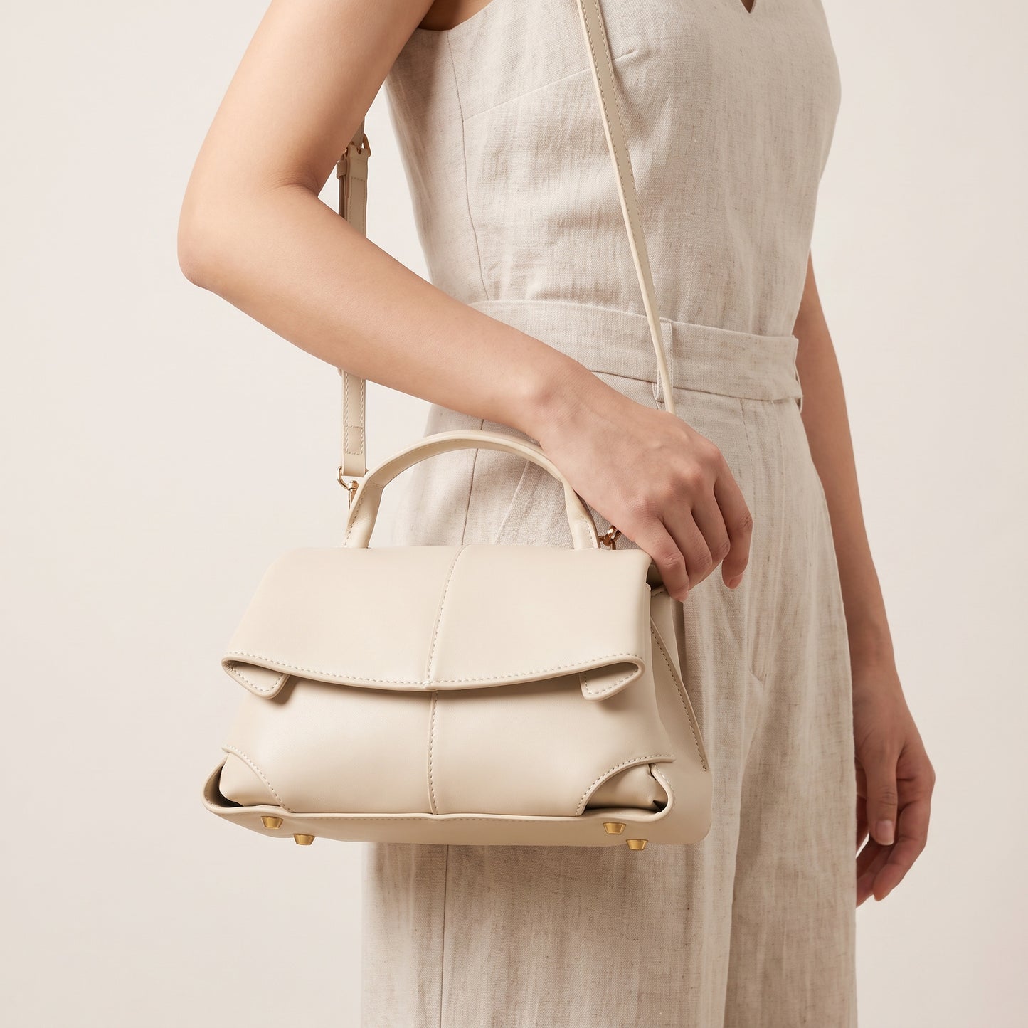 Model holding the Cream Fiorella mini leather baguette by the handle, studio shot
