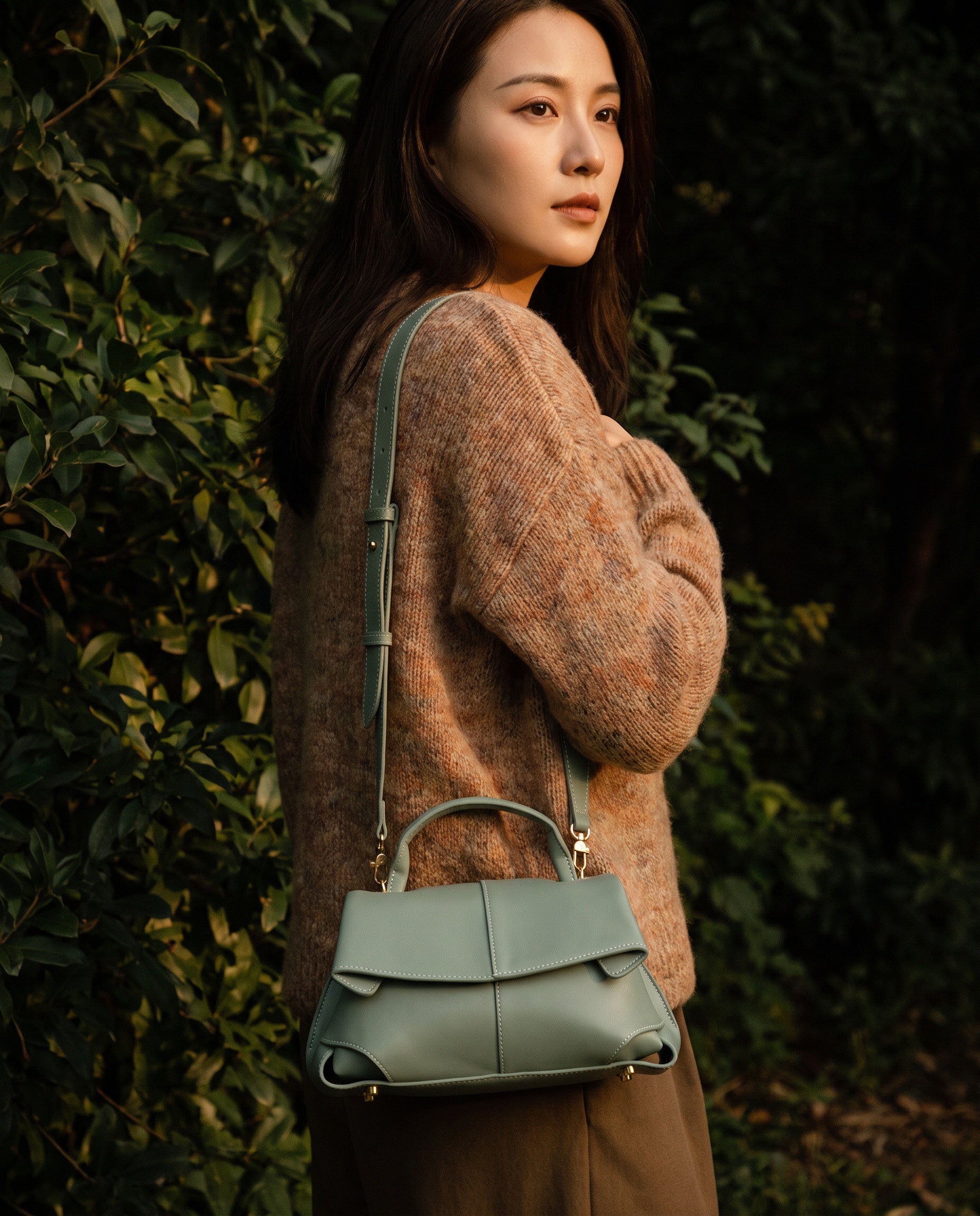Woman with the Sage Green Fiorella bag crossbody against green foliage