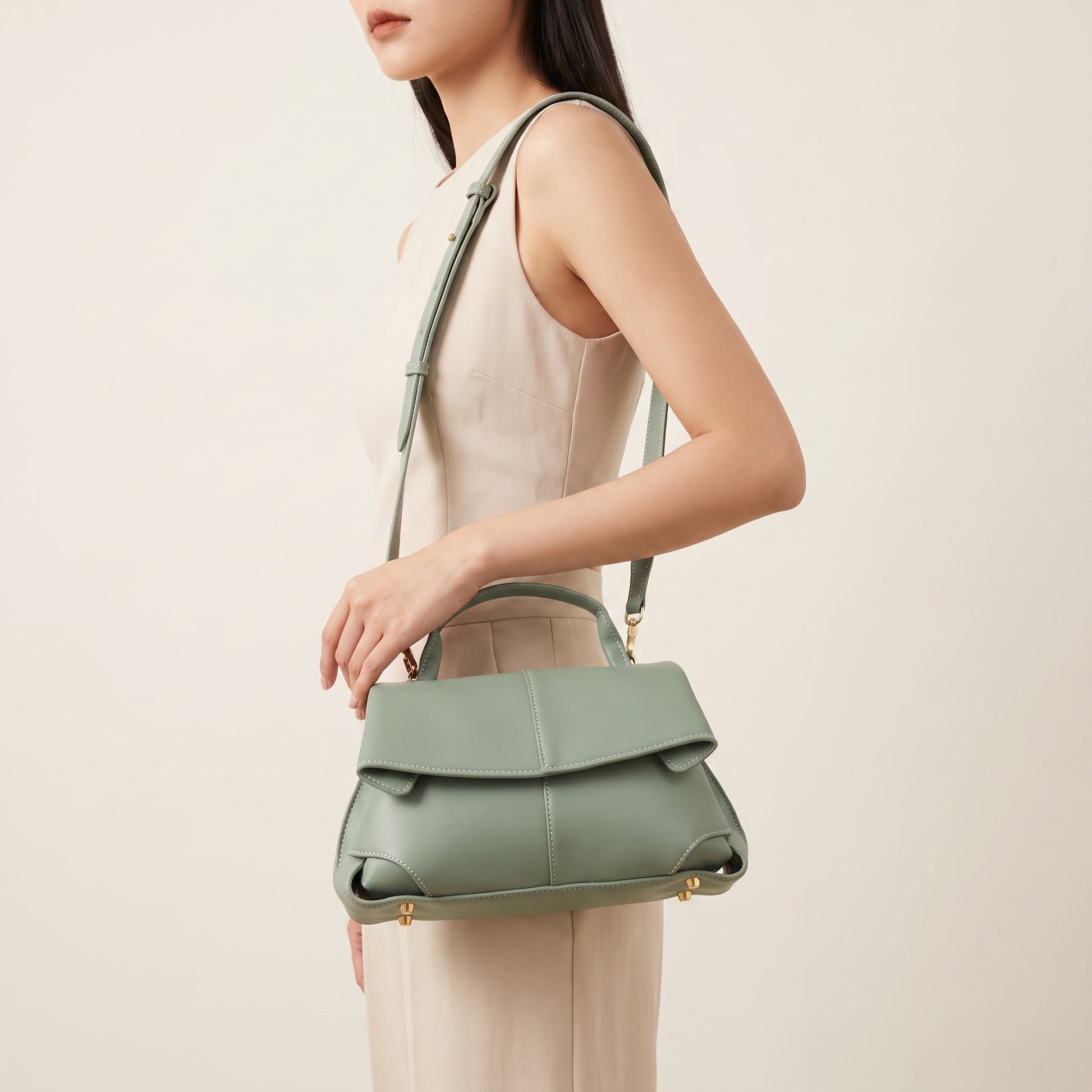 Model carrying the Sage Green Fiorella mini leather baguette crossbody, studio shot
