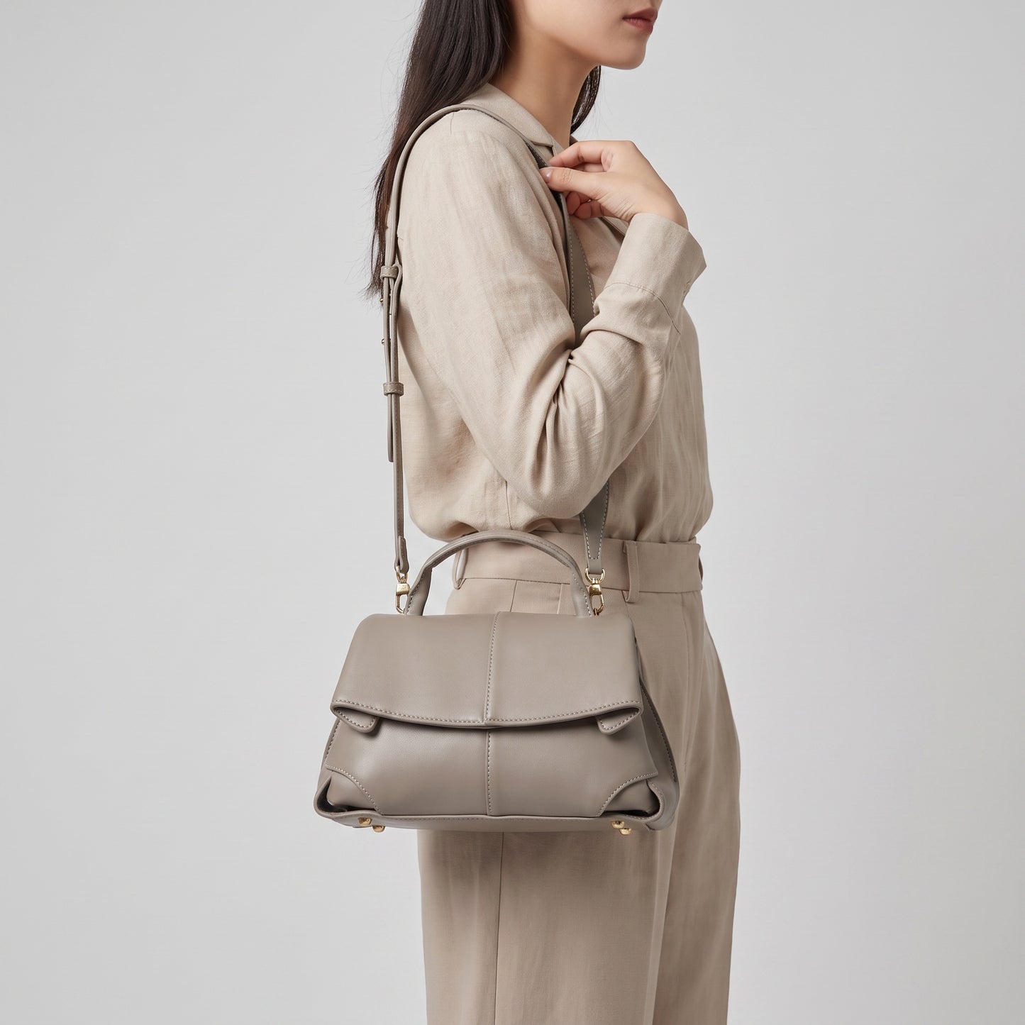 Model holding the Taupe Fiorella mini leather baguette by the handle, studio shot