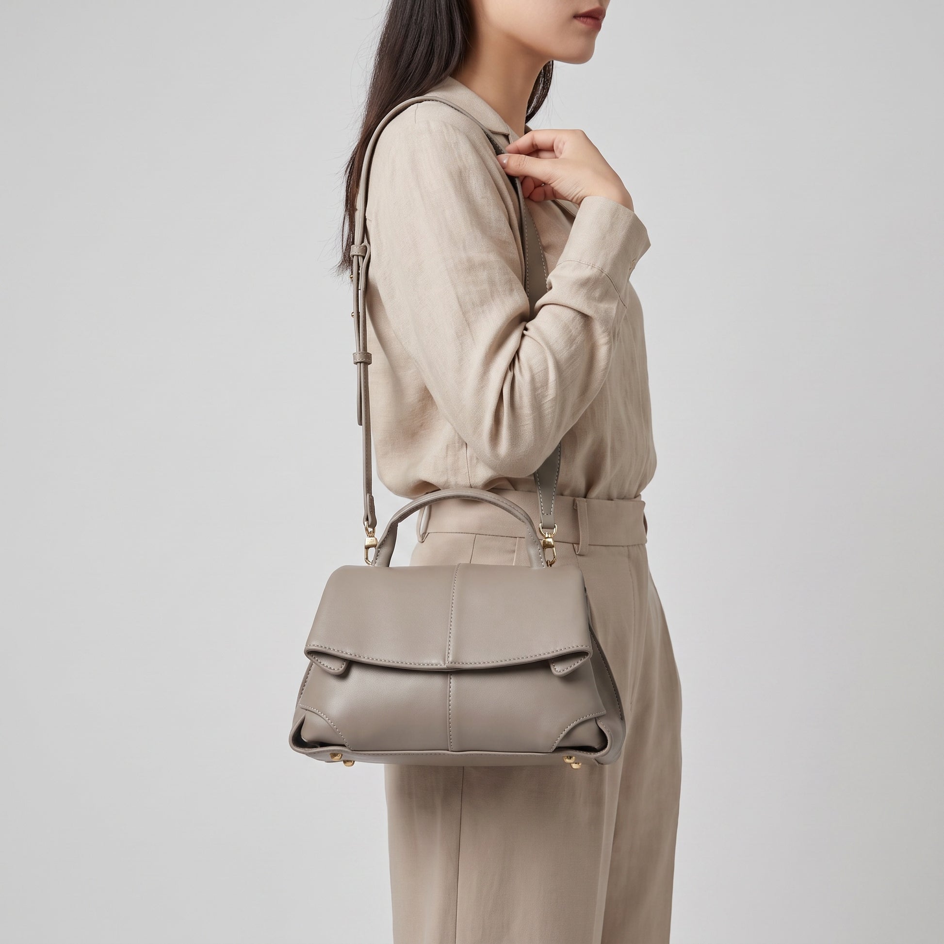 Model holding the Taupe Fiorella mini leather baguette by the handle, studio shot