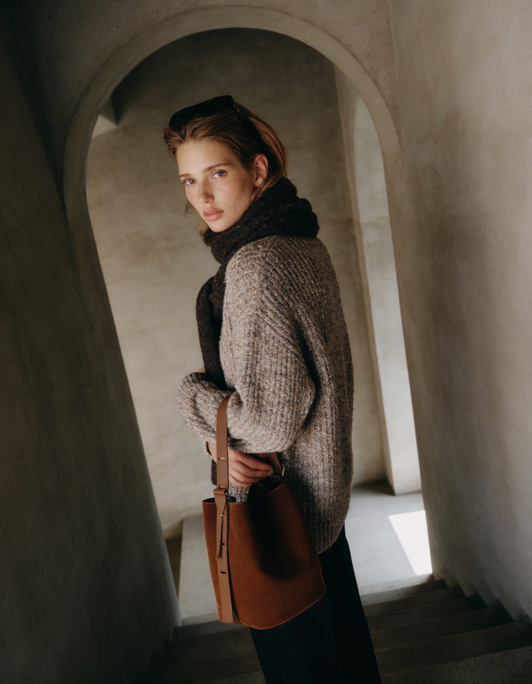 Woman carrying the Chocolate Serena bucket bag in a tweed coat