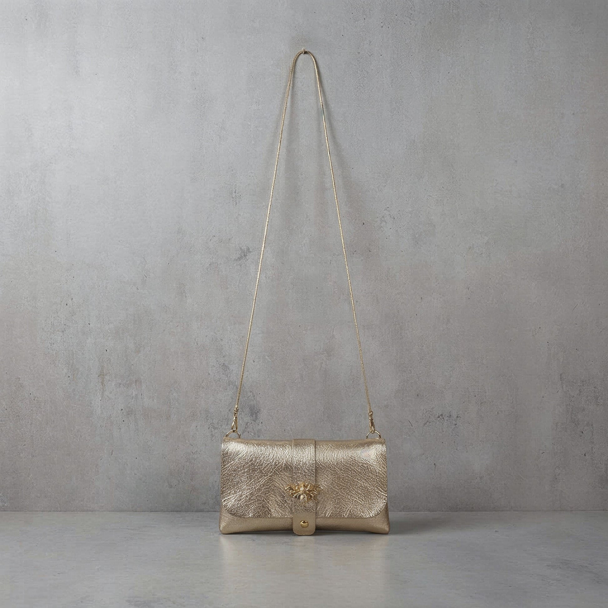 Anima Suede Leather Metallic Clutch Shoulder Bag by Clemés in Champagne, studio shot on grey background