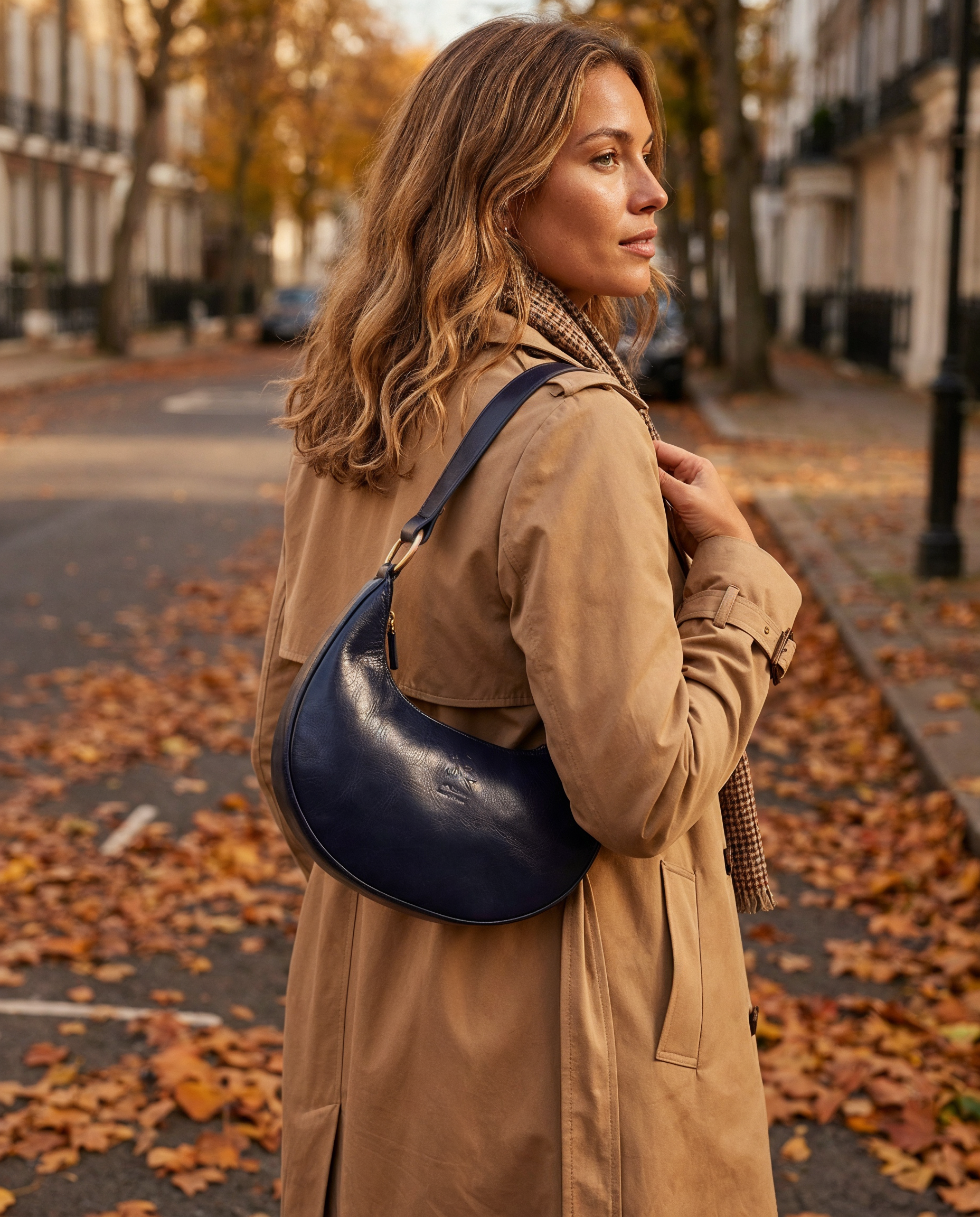 Woman wearing the Navy Mezzaluna bag on her shoulder in a trench coat