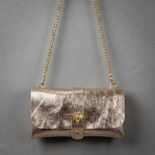 Model carrying the Champagne Anima clutch on its chain strap, studio shot