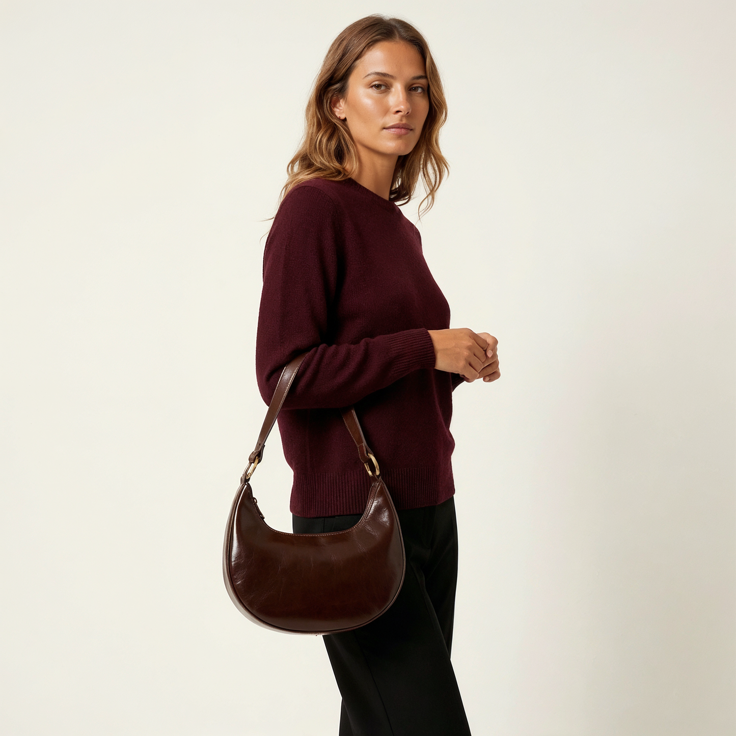 Woman wearing the Chocolate Mezzaluna bag on her shoulder in a burgundy sweater