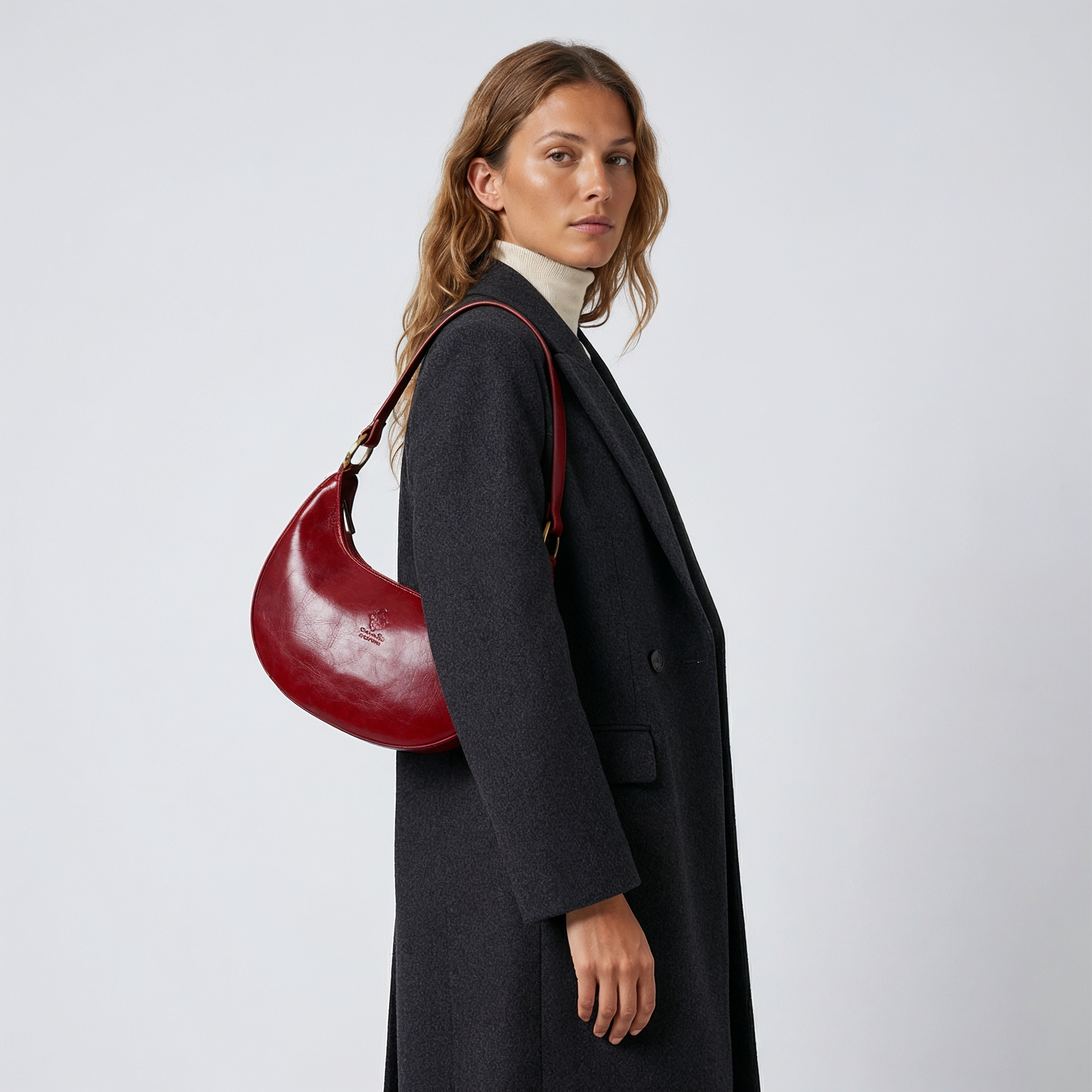 Woman wearing the Dark Red Mezzaluna bag on her shoulder in a black coat
