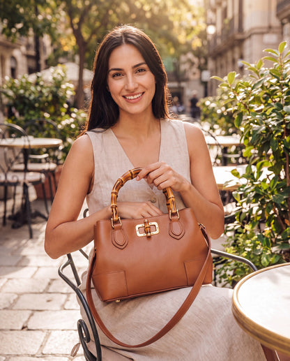 Woman with the Medium Ginevra bamboo-handle leather bag in Cognac at a sunlit café terrace