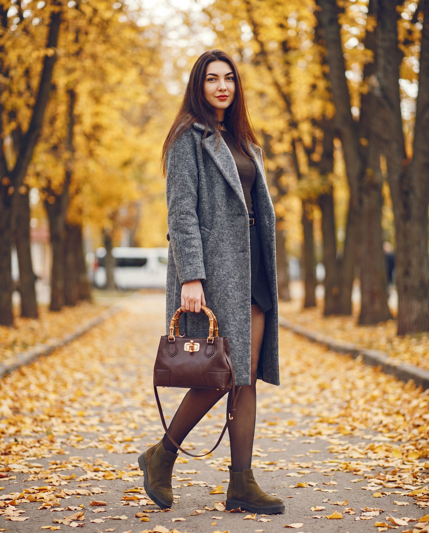 Woman with the Medium Ginevra bamboo-handle leather bag in Dark Brown on an autumn street