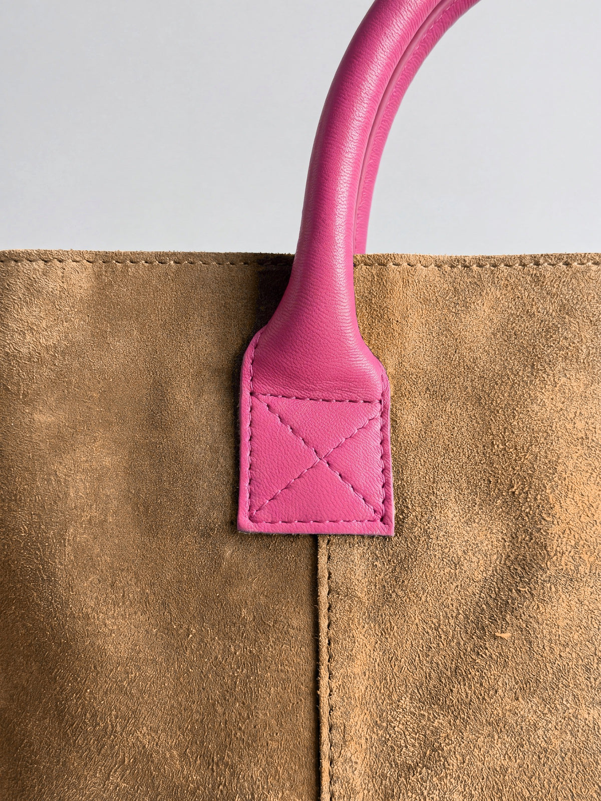 Milano Max Suede Bag in Tan by Clemés, macro detail of the fuchsia pink leather handle tab with cross stitching on tan suede