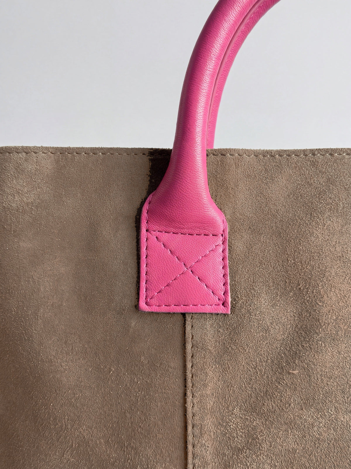 Milano Max Suede Bag in Taupe by Clemés, macro detail of the fuchsia pink leather handle tab with cross stitching on taupe suede