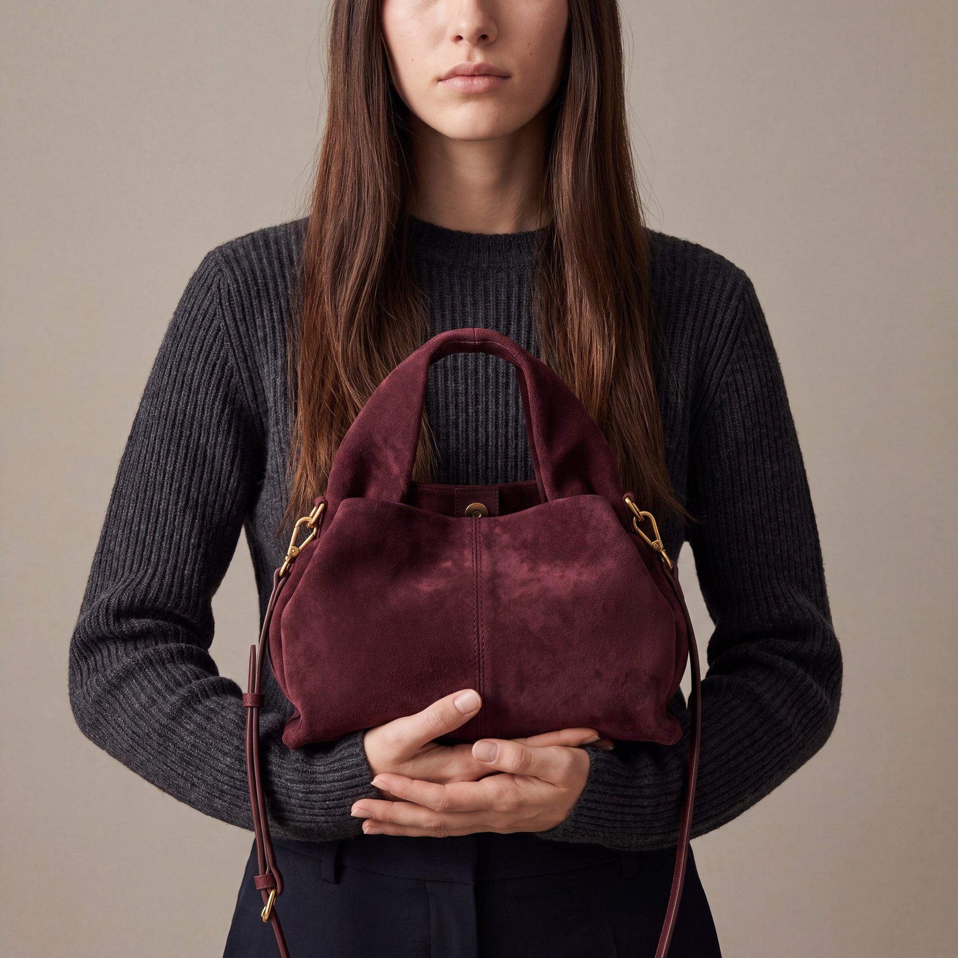 Model holding the Burgundy Noemi Suede Handbag with both hands at waist height, studio shot