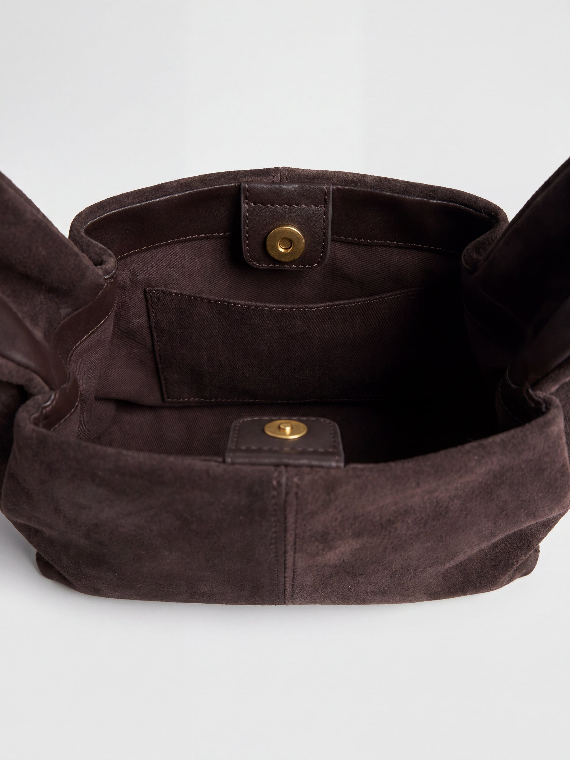 Inside the Dark Brown Noemi Suede Handbag showing the fabric lining, internal slip pocket and gold press studs