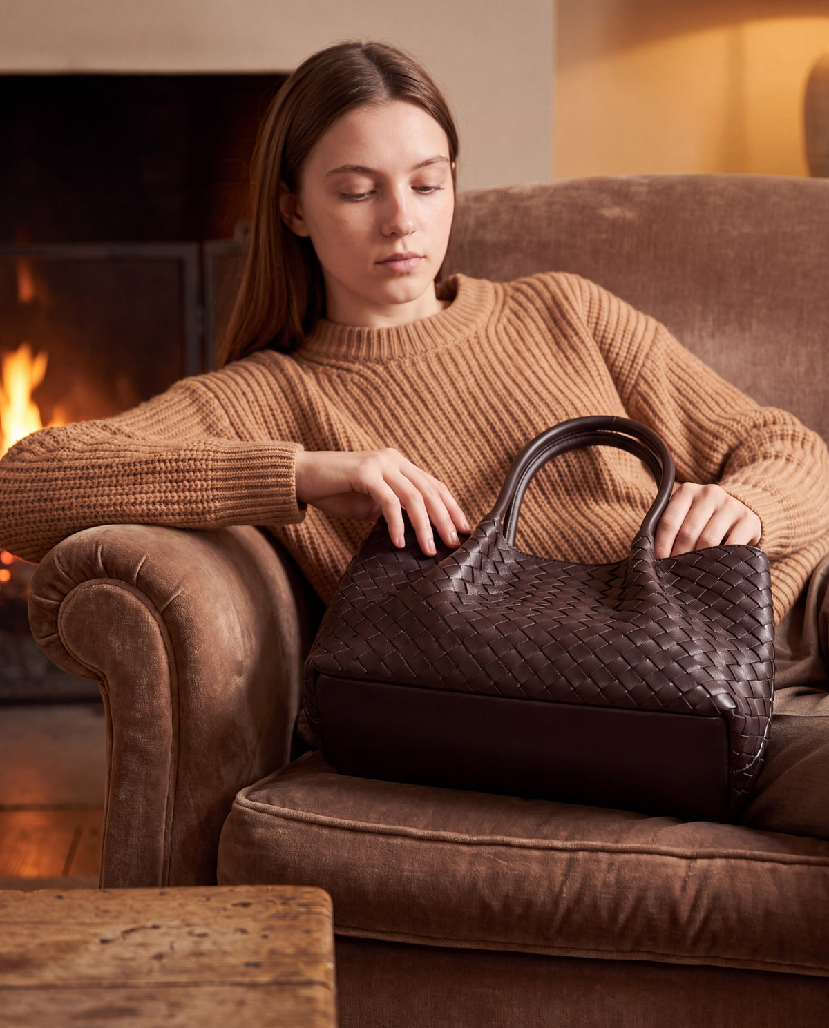 Woman with the Dark Brown Ornella woven leather bag by a fireside