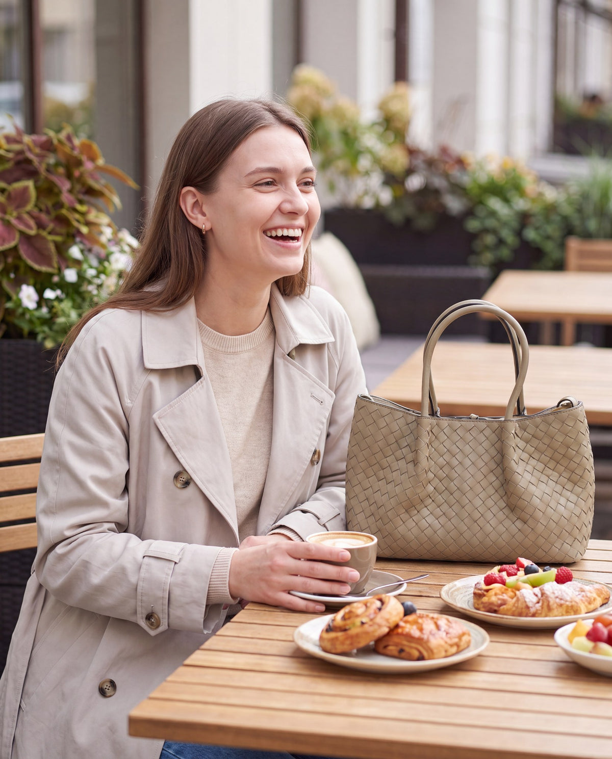 Woman with the Taupe Ornella woven leather bag at an outdoor brunch table