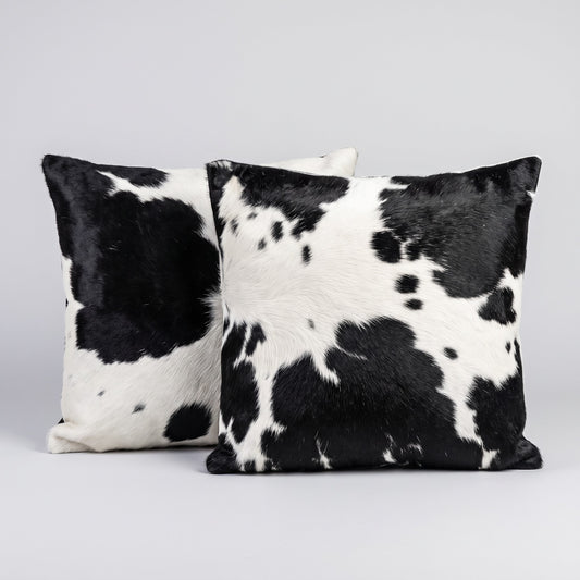 Pair of black and white genuine cowhide cushion covers on a grey studio backdrop
