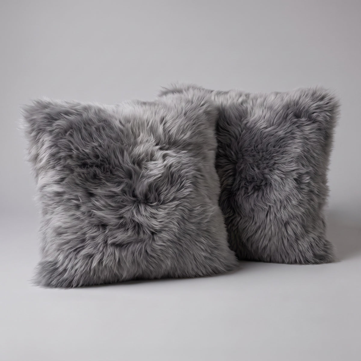Pair of Dover Grey New Zealand sheepskin cushion covers 35 x 35 cm on a grey studio backdrop