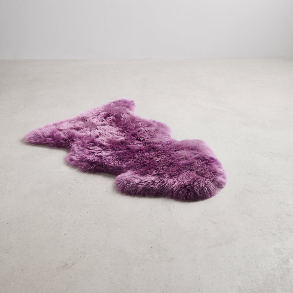 Medici purple single sheepskin rug laid flat on a pale grey floor