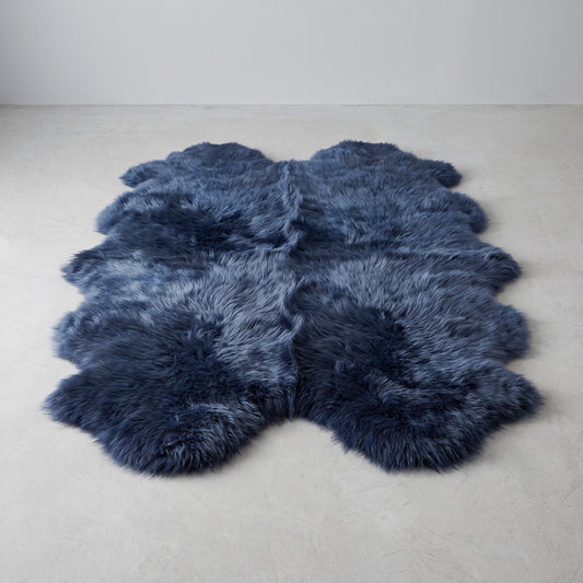 Indigo navy quad New Zealand sheepskin rug, L180 x W105 cm, on a pale grey studio floor