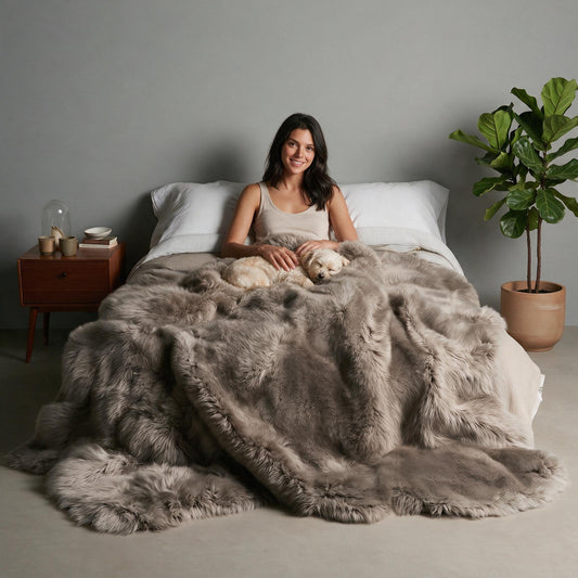Taupe Octo New Zealand sheepskin rug throw styled on a bed, model with a small dog curled in her lap