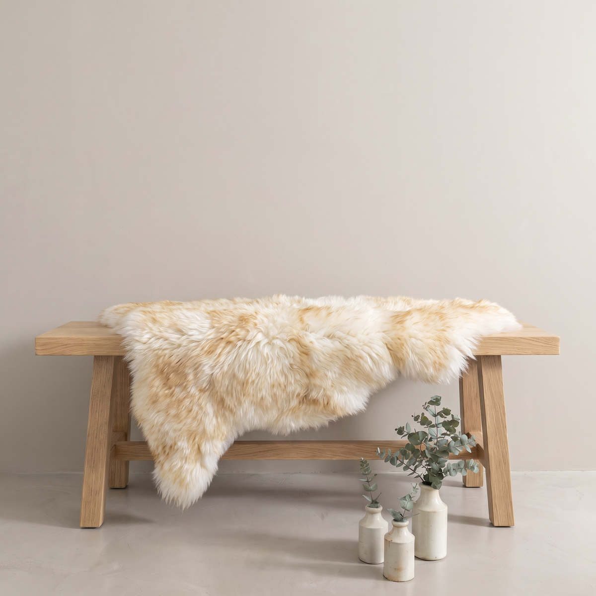 Dusk sheepskin rug draped over an oak bench in a minimal interior