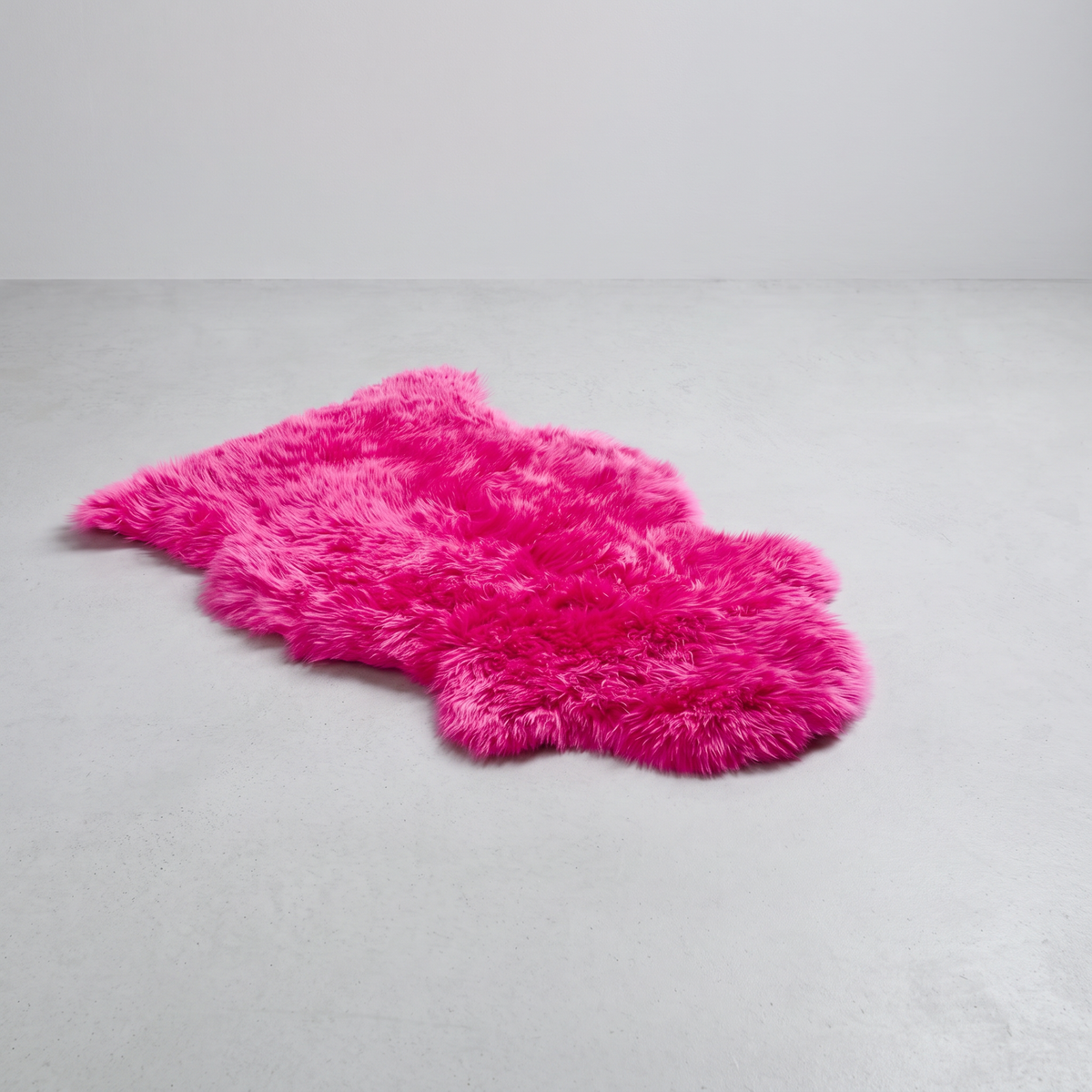 Fuchsia single sheepskin rug laid flat on a pale grey floor