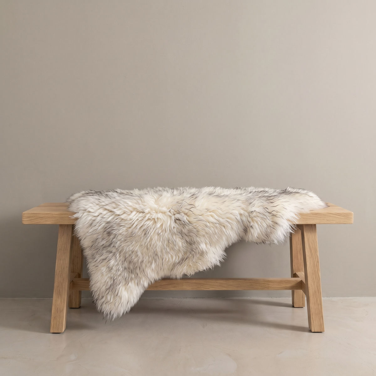 Twilight sheepskin rug draped over an oak bench in a minimal interior