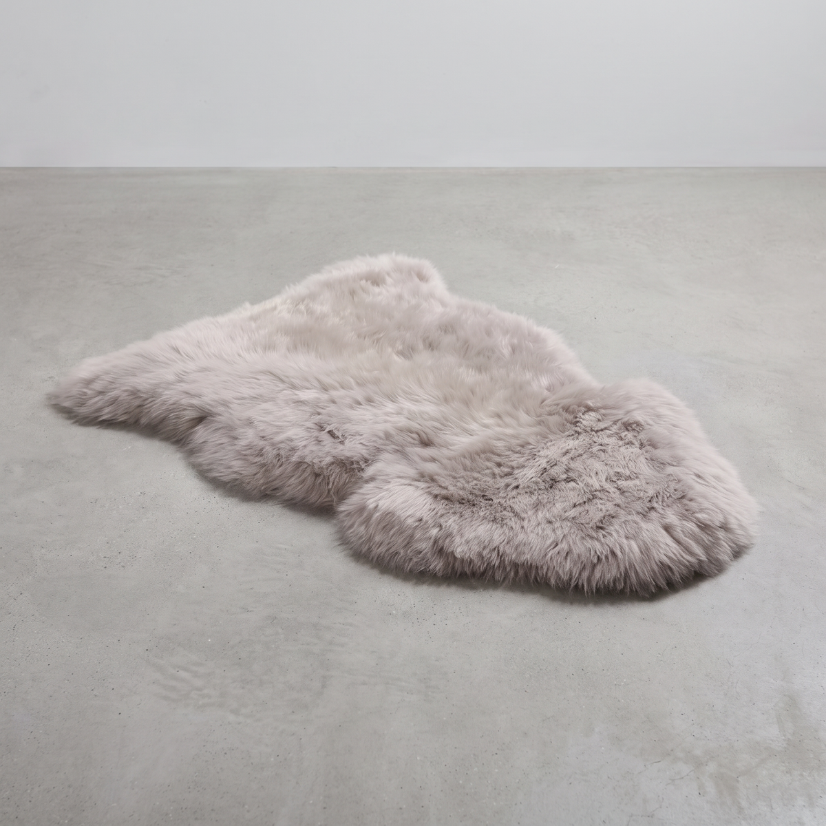 Light Grey single sheepskin rug laid flat on a pale grey floor