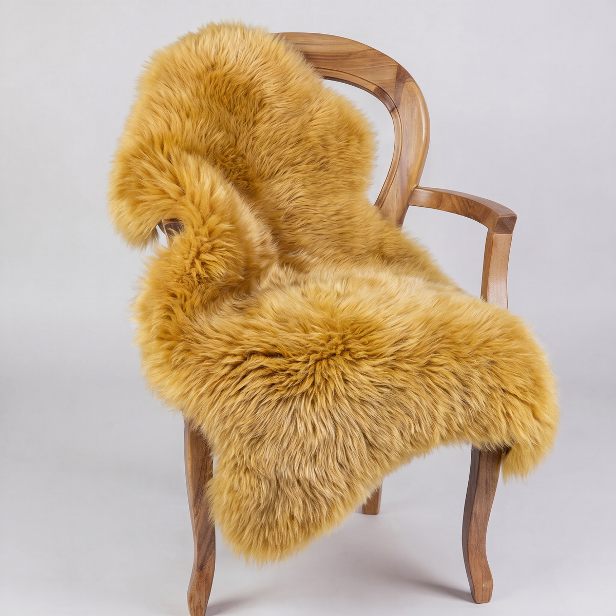 Squash golden sheepskin rug draped over a wooden armchair, front three-quarter view