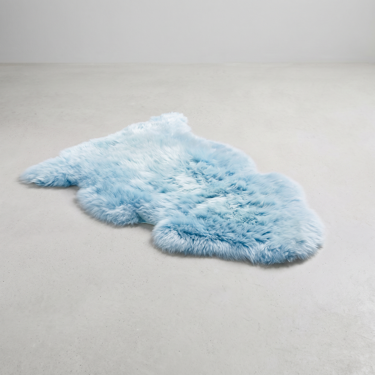 Sea Foam single sheepskin rug laid flat on a pale grey floor