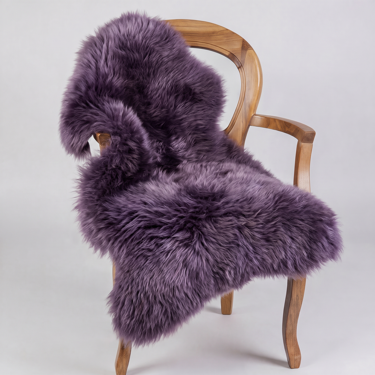 Purple sheepskin rug draped over a wooden armchair, front three-quarter view