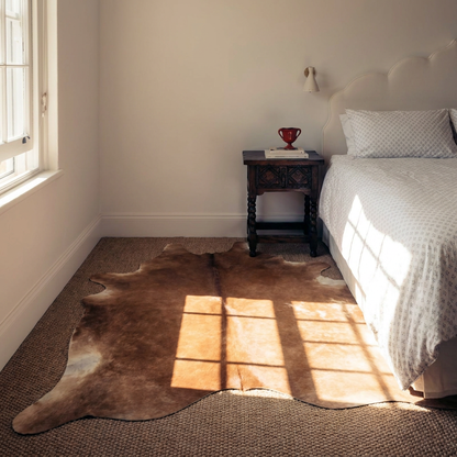 Caramel and ivory exotic printed cowhide rug styled on the floor of an editorial interior
