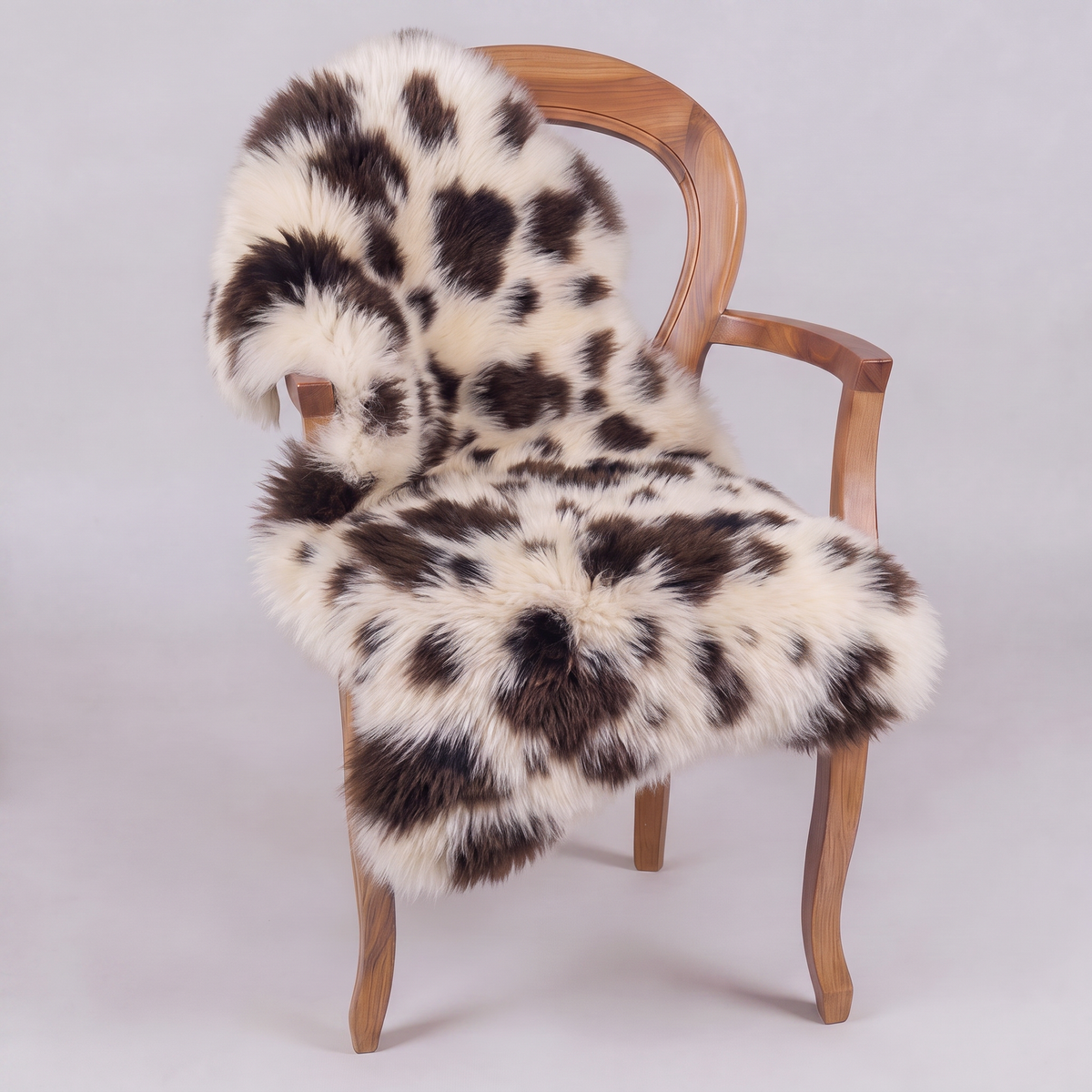 Printed Jacob single sheepskin rug draped over a wooden armchair, front three-quarter view