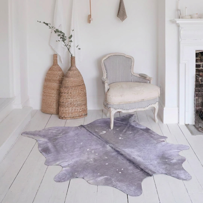 Lilac metallic cowhide rug styled on white painted floorboards in a soft romantic all-white sitting room