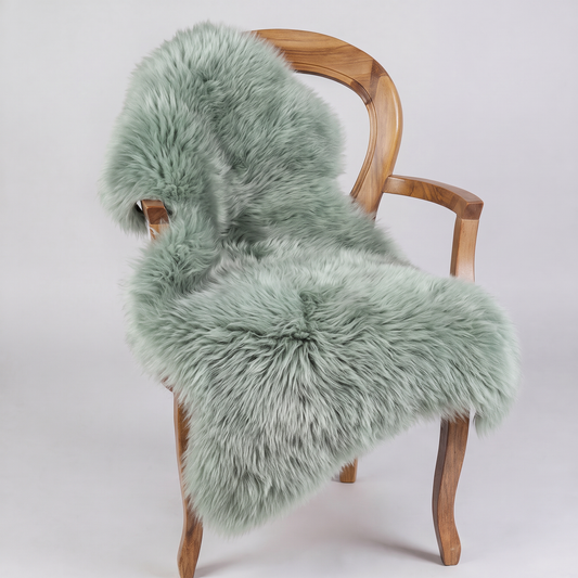 Sage green sheepskin rug draped over a wooden armchair, front three-quarter view