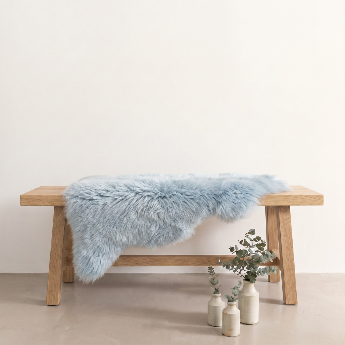 Sea Foam sheepskin rug draped over an oak bench in a minimal interior