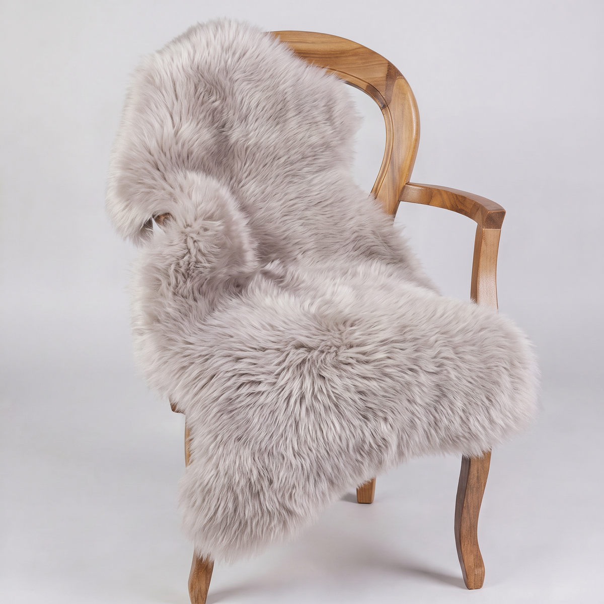 Light Grey sheepskin rug draped over a wooden armchair, front three-quarter view