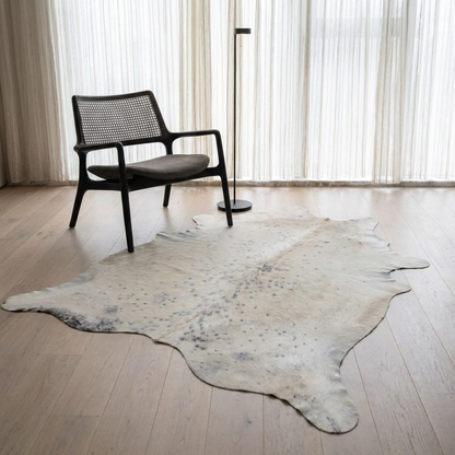 Caramel and ivory exotic printed cowhide rug styled on the floor of an editorial interior
