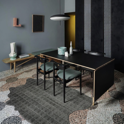Charcoal snakeskin-embossed cowhide rug styled on the terrazzo floor of a moody luxe grey-green dining room