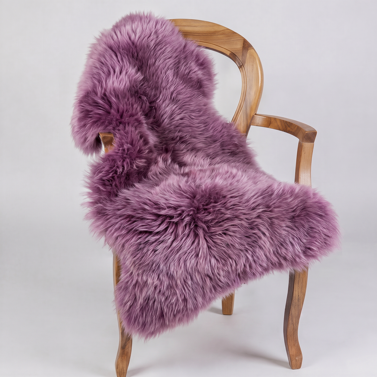 Medici purple sheepskin rug draped over a wooden armchair, front three-quarter view