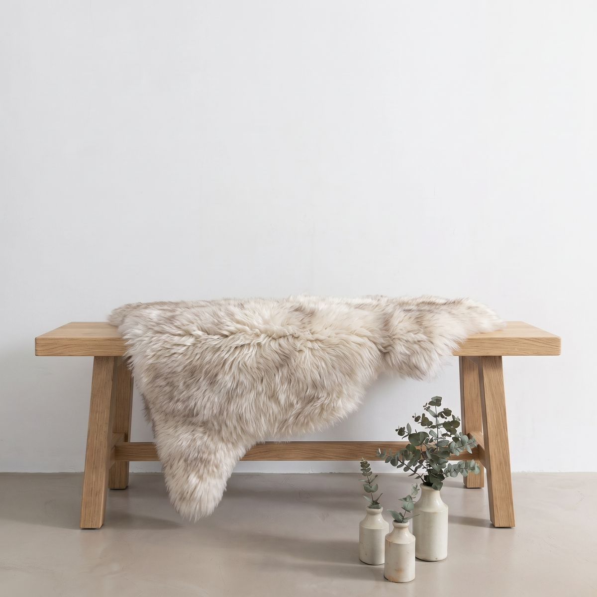 Wolf Tip sheepskin rug draped over an oak bench in a minimal interior