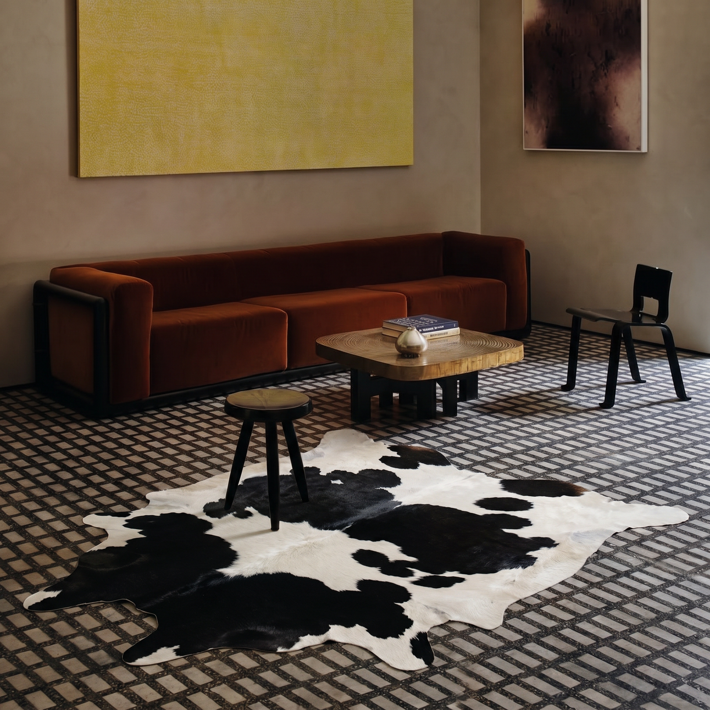 Black and white cowhide rug styled on the floor of a moody tile-floor living room