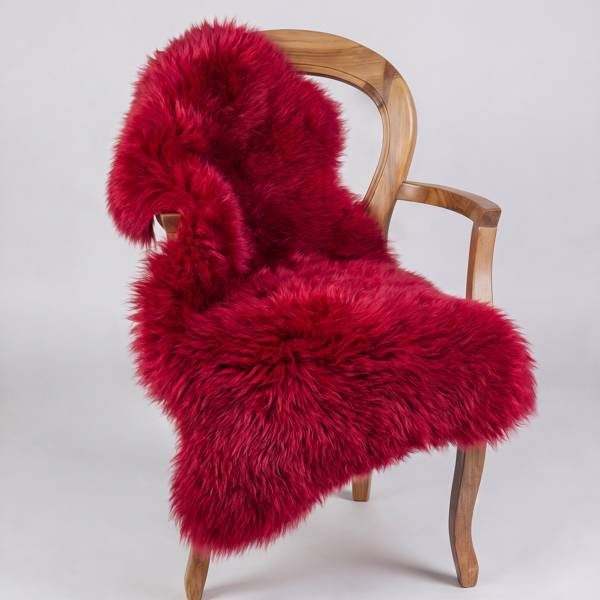 Wildfire red sheepskin rug draped over a wooden armchair, front three-quarter view