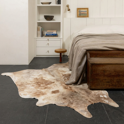 Caramel and ivory exotic printed cowhide rug styled on the floor of an editorial interior